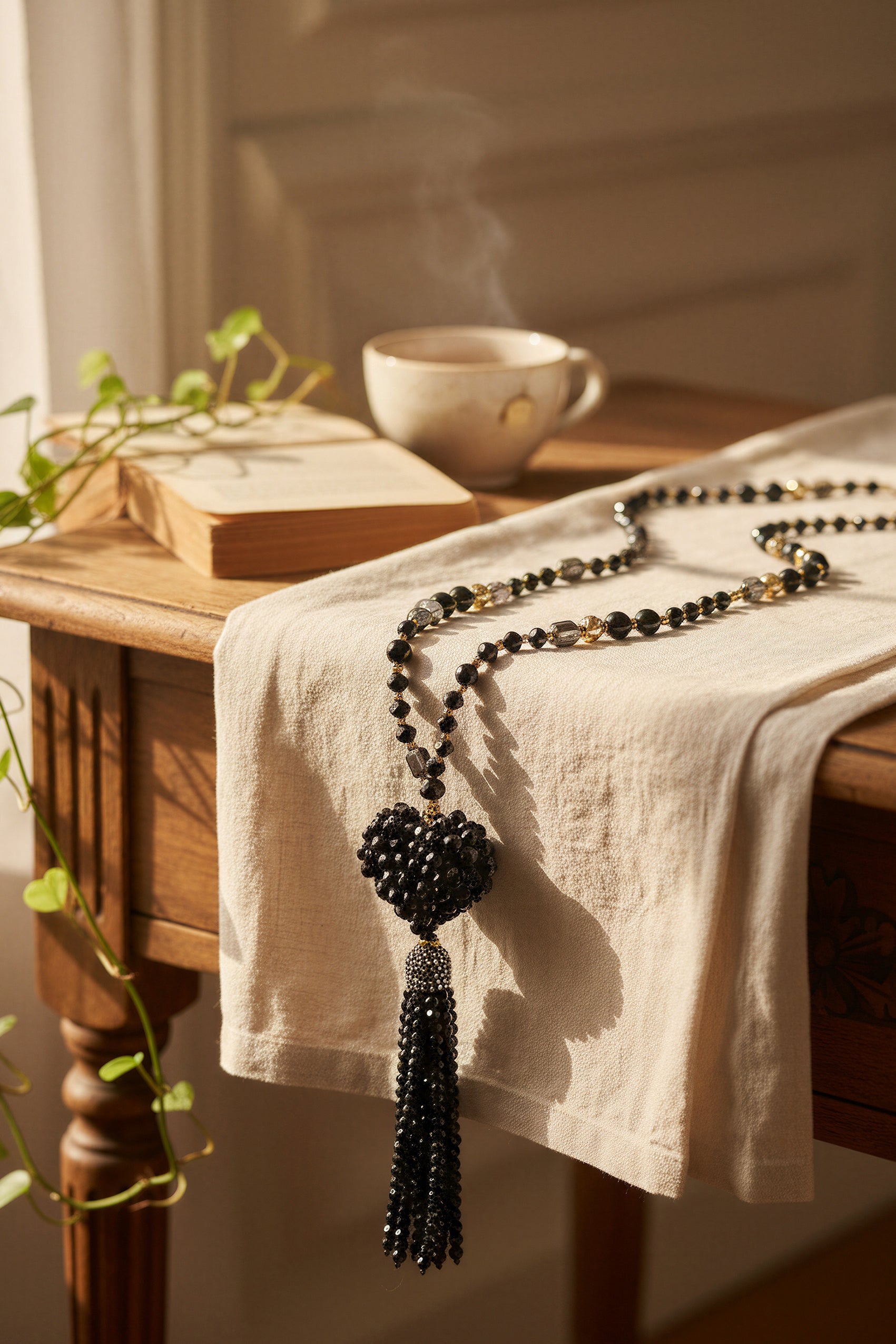 Lange schwarze Glasperlenkette mit funkelndem Herz und Steinchen-Quaste